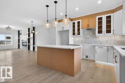 Open-concept kitchen and living area featuring a central island with wood-finish paneling, white countertops, and three pendant light fixtures - 