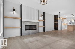 Living space featuring a linear electric fireplace with a textured surround, integrated wood-finish shelving, and light wood-finish flooring - 