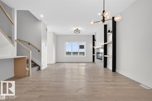 Open-concept living area featuring wood-finish flooring, a contemporary fireplace with mantel, and built-in shelving - 43 River Birch Way, St. Albert, AB - Indoor Photo Showing Other Room