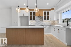 Contemporary kitchen featuring a wood-finish island with a light-toned countertop, complemented by three pendant lights - 