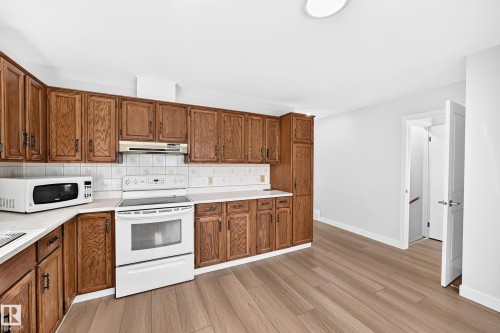 Kitchen featuring extensive wood cabinetry, white countertops, and a white tile backsplash - 6208 11 Ave Nw Nw, Edmonton, AB - Indoor Photo Showing Kitchen