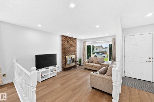 Living area with wood-finish flooring, recessed lighting, and a brick-faced fireplace with a brass-tone insert - 6208 11 Ave Nw Nw, Edmonton, AB - Indoor Photo Showing Other Room