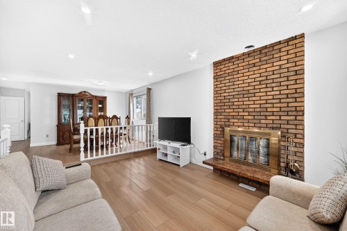 Brick-faced fireplace with a brass-trimmed insert and stone hearth - 6208 11 Ave Nw Nw, Edmonton, AB - Indoor Photo Showing Living Room With Fireplace
