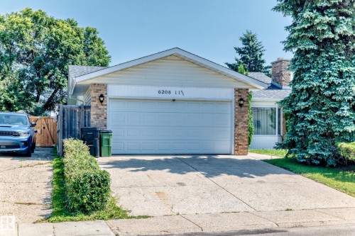 Front exterior featuring a white garage door, brick accents, and a concrete driveway - 6208 11 Ave Nw Nw, Edmonton, AB - Outdoor
