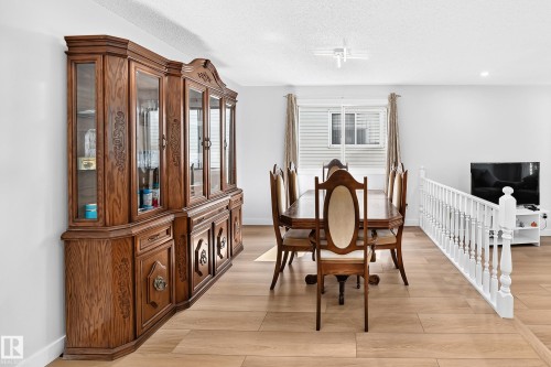 Open-concept dining area featuring light wood-finish flooring, white painted walls, and a white baluster railing - 6208 11 Ave Nw Nw, Edmonton, AB - Indoor Photo Showing Dining Room