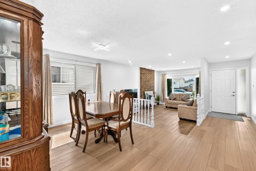 Open concept living area featuring wood-finish flooring, recessed lighting, and a brick accent wall - 6208 11 Ave Nw Nw, Edmonton, AB - Indoor