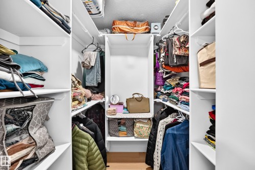 Walk-in closet featuring built-in white shelving, hanging rods, and wood-finish flooring - 6208 11 Ave Nw Nw, Edmonton, AB - Indoor With Storage