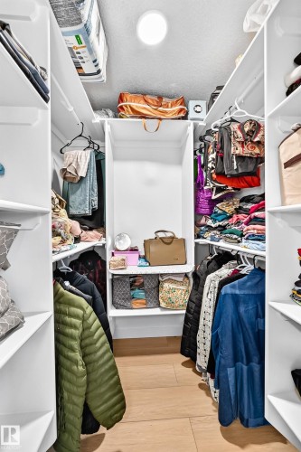 Walk-in closet featuring light wood-finish flooring, white built-in shelving, multiple hanging rods, and recessed ceiling lighting - 6208 11 Ave Nw Nw, Edmonton, AB - Indoor With Storage