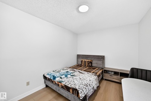 Room featuring light wood-finish flooring, white painted walls, and a textured ceiling - 6208 11 Ave Nw Nw, Edmonton, AB - Indoor Photo Showing Bedroom