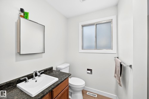 Bathroom featuring a wood-finish vanity with a dark countertop and integrated white sink - 6208 11 Ave Nw Nw, Edmonton, AB - Indoor Photo Showing Bathroom