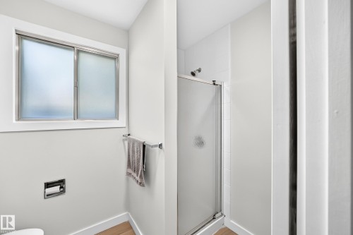 Bathroom featuring a frosted window, chrome towel bar, and a shower enclosure with a clear glass door - 6208 11 Ave Nw Nw, Edmonton, AB - Indoor