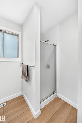 Shower enclosure with a sliding frosted glass door, white wall tiling, and chrome fixtures - 6208 11 Ave Nw Nw, Edmonton, AB - Indoor Photo Showing Other Room