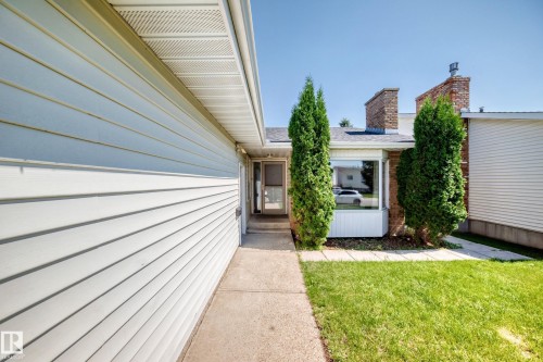 Exterior siding with white horizontal panels, a concrete walkway, and a landscaped front yard with green grass - 6208 11 Ave Nw Nw, Edmonton, AB - Outdoor