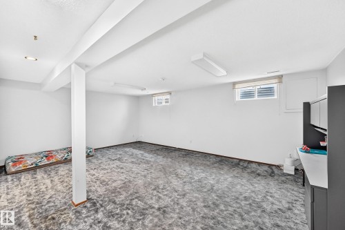 Spacious basement room featuring white walls, gray patterned carpeting, recessed lighting, and a built-in cabinetry unit with white countertops - 6208 11 Ave Nw Nw, Edmonton, AB - Indoor Photo Showing Basement