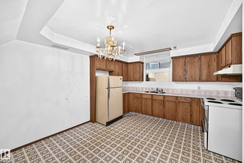 Kitchen featuring wood cabinetry, patterned flooring, and a crystal chandelier - 6208 11 Ave Nw Nw, Edmonton, AB - Indoor Photo Showing Kitchen With Double Sink