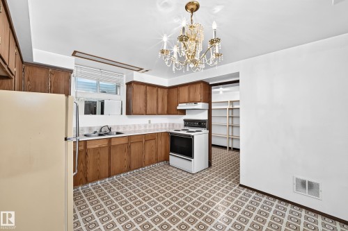 Kitchen featuring wood cabinetry, a built-in oven with range hood, and a dual-basin sink - 6208 11 Ave Nw Nw, Edmonton, AB - Indoor Photo Showing Kitchen With Double Sink