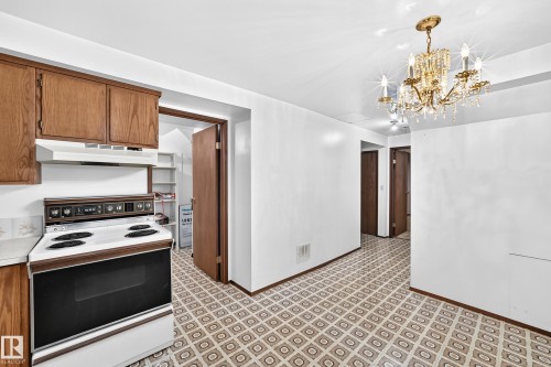 Kitchen area featuring a built-in electric range with a white finish, wood-finish cabinetry, and a patterned floor - 6208 11 Ave Nw Nw, Edmonton, AB - Indoor Photo Showing Kitchen