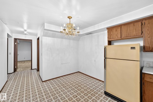 Dining area featuring a chandelier light fixture, patterned floor tiling, and wood cabinetry - 6208 11 Ave Nw Nw, Edmonton, AB - Indoor Photo Showing Kitchen