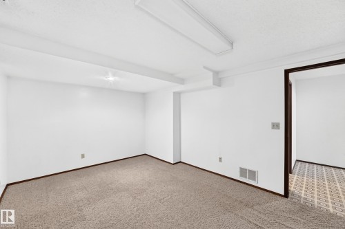 Carpeted room with white walls, dark wood trim, and an exposed ceiling beam - 6208 11 Ave Nw Nw, Edmonton, AB - Indoor Photo Showing Other Room