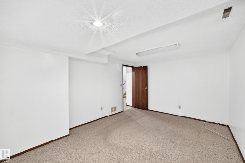 Spacious room featuring neutral carpet flooring, white painted walls, recessed lighting, and a wood-finish door frame - 6208 11 Ave Nw Nw, Edmonton, AB - Indoor Photo Showing Other Room
