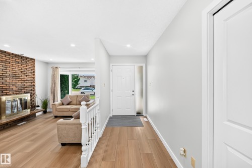 Entryway featuring wood-finish flooring, a white front door with sidelight, and a partial white baluster railing - 6208 11 Ave Nw Nw, Edmonton, AB - Indoor With Fireplace