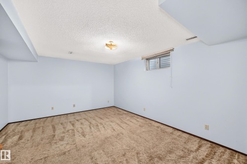 Spacious room featuring light blue walls, brown patterned carpet, and a textured ceiling - 6208 11 Ave Nw Nw, Edmonton, AB - Indoor Photo Showing Other Room