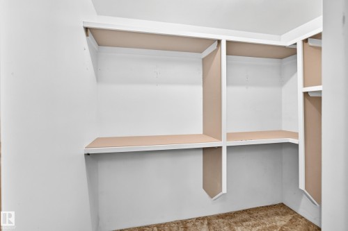 Walk-in closet featuring white painted walls, built-in shelving, and a neutral-toned subfloor - 6208 11 Ave Nw Nw, Edmonton, AB - Indoor