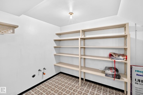 Dedicated utility space featuring extensive built-in shelving, patterned floor tiles, and utility hookups - 6208 11 Ave Nw Nw, Edmonton, AB - Indoor Photo Showing Other Room