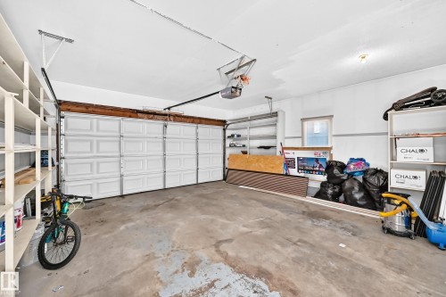 Spacious garage featuring a two-car garage door, concrete flooring, built-in shelving, and a single window for natural light - 6208 11 Ave Nw Nw, Edmonton, AB - Indoor Photo Showing Garage