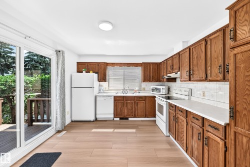 Kitchen featuring wood-finish cabinetry, white countertops, a tile backsplash, and light wood-finish flooring - 6208 11 Ave Nw Nw, Edmonton, AB - Indoor Photo Showing Kitchen