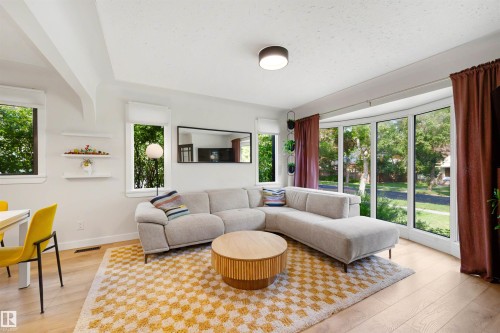 Bright living area featuring wood-finish flooring and a tray ceiling - 10732 129 Street Nw, Edmonton, AB - Indoor Photo Showing Living Room