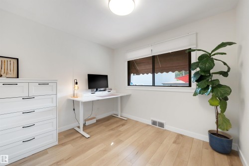 Light wood-finish flooring complements white walls and trim - 10732 129 Street Nw, Edmonton, AB - Indoor