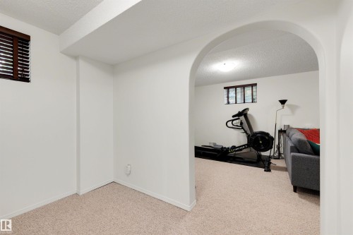 Archway entry to a carpeted room with a window featuring horizontal wood blinds - 10732 129 Street Nw, Edmonton, AB - Indoor Photo Showing Other Room