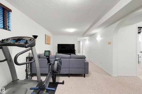 Spacious room featuring light-toned carpet flooring, white walls, recessed ceiling lighting, and a window with horizontal blinds - 10732 129 Street Nw, Edmonton, AB - Indoor Photo Showing Gym Room