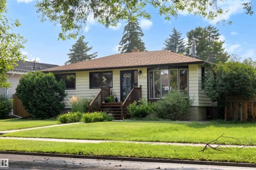 Ranch-style residence featuring light-colored siding, a brown shingle roof, and a prominent bay window - 10732 129 Street Nw, Edmonton, AB - Outdoor