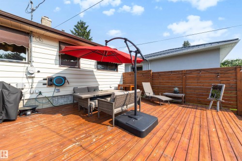 Spacious outdoor wood-finish deck featuring a privacy fence, string lighting, and direct exterior access - 10732 129 Street Nw, Edmonton, AB - Outdoor With Deck Patio Veranda With Exterior