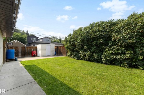 Expansive backyard featuring a lush lawn, concrete patio, and a dedicated storage shed - 10732 129 Street Nw, Edmonton, AB - Outdoor