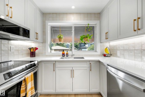 Modern kitchen featuring white shaker-style cabinetry with gold-tone hardware, a stainless steel range, and a built-in microwave - 10732 129 Street Nw, Edmonton, AB - Indoor Photo Showing Kitchen With Upgraded Kitchen