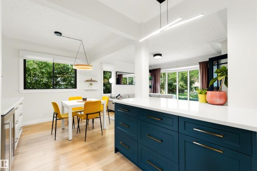 Open-concept kitchen and dining area featuring a spacious island with blue cabinetry, a white countertop, and light wood-finish flooring - 10732 129 Street Nw, Edmonton, AB - Indoor