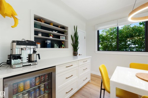 Integrated beverage bar featuring white shaker cabinetry, light-toned countertop, and an under-counter beverage cooler - 10732 129 Street Nw, Edmonton, AB - Indoor