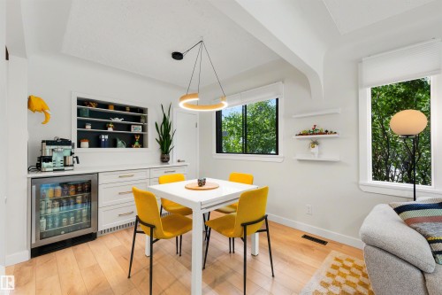 Open-concept space featuring light wood-finish flooring and a built-in beverage center with a glass-front mini-fridge - 10732 129 Street Nw, Edmonton, AB - Indoor Photo Showing Dining Room