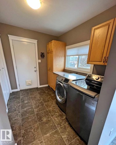 Bathroom featuring a built-in vanity with a white basin sink and wood-finish cabinetry, a toilet, and a shower with a white surround - 3003 Park Avenue, Mallaig, AB - Indoor Photo Showing Bathroom