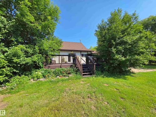 Expansive backyard with a large lawn, mature trees, and a spacious rear deck - 3003 Park Avenue, Mallaig, AB - Outdoor
