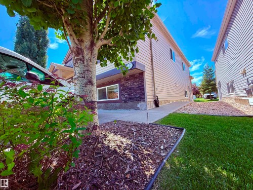 Exterior siding with stone veneer accents and a large lower-level window - 122 142 Selkirk Place, Leduc, AB - Outdoor