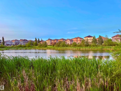 Lakeside residences featuring varied architectural styles and mature landscaping along the water's edge - 122 142 Selkirk Place, Leduc, AB - Outdoor With Body Of Water With View