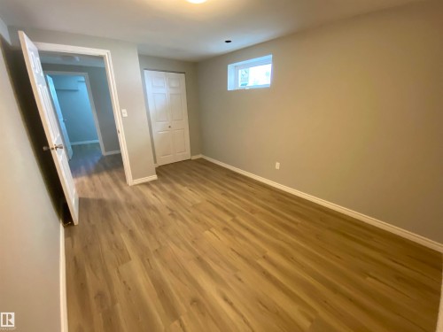 Room featuring wood-finish flooring, a bi-fold closet, and a white-trimmed window - 12010 66 Street Nw, Edmonton, AB - Indoor Photo Showing Other Room