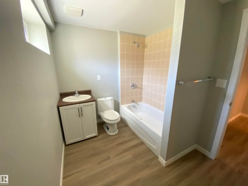 Bathroom featuring a white vanity with a dark countertop, an integrated sink, and white cabinetry - 12010 66 Street Nw, Edmonton, AB - Indoor Photo Showing Bathroom