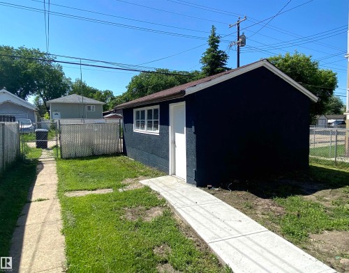 Detached structure featuring dark blue siding, a white entry door, and a multi-pane window - 12010 66 Street Nw, Edmonton, AB - Outdoor