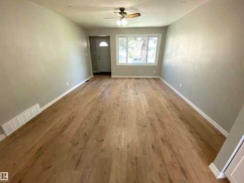 Spacious room featuring wood-finish flooring, light gray walls, and white trim - 12010 66 Street Nw, Edmonton, AB - Indoor Photo Showing Other Room