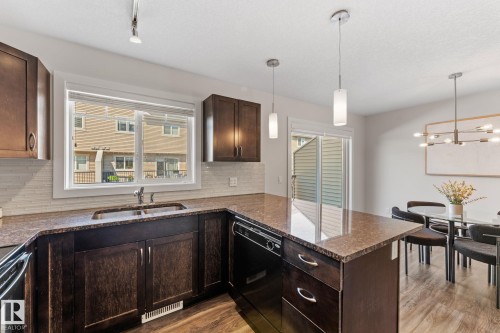 Kitchen featuring dark wood cabinetry, a granite-finish countertop, and a tiled backsplash - #18 7289 South Terwillegar Dr Nw, Edmonton, AB - Indoor Photo Showing Kitchen With Double Sink